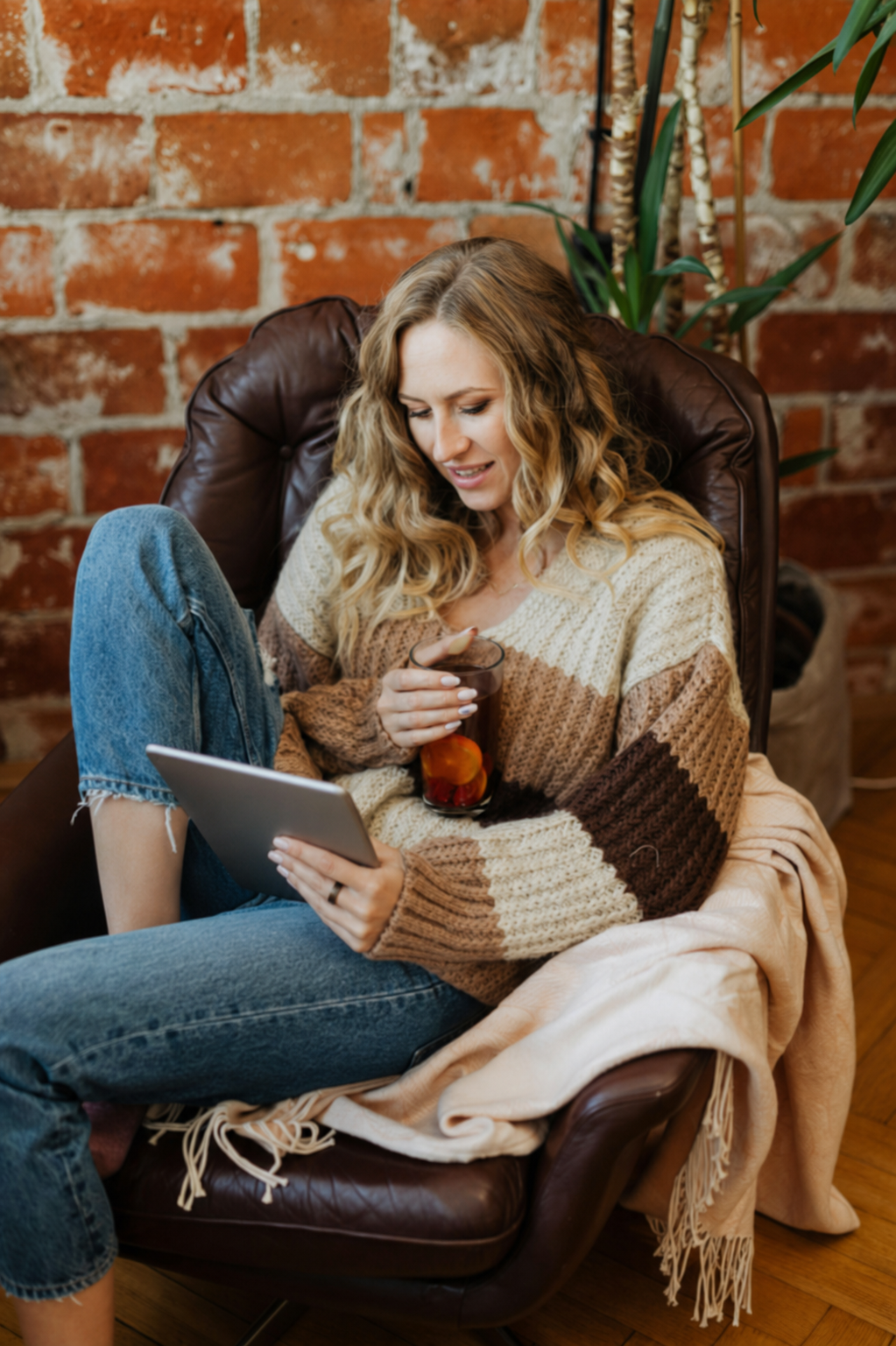 Woman reading an ebook on a tablet in a cosy armchair